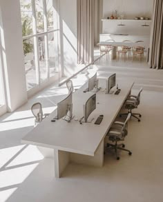 an office with multiple computer screens and desks in front of large windows that look out onto the outdoors