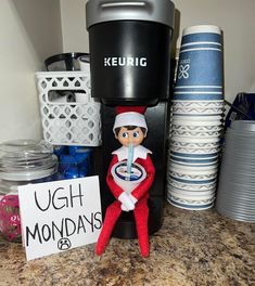 an elf is sitting in front of a coffee maker with a sign that says ugh mondays