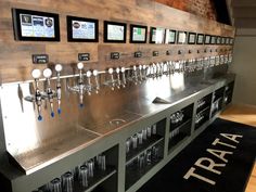 a row of beer taps sitting on top of a metal counter next to a black rug