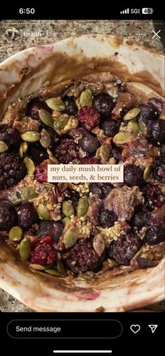 a bowl filled with fruit and nuts sitting on top of a stone counter next to a cell phone