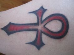 an artistic tattoo on the leg of a woman with red and black cross in it