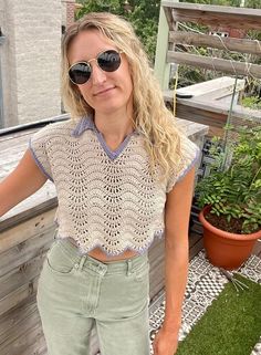 a woman wearing sunglasses standing on a deck next to a potted plant and wooden fence