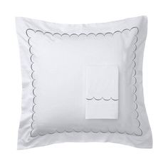 a white pillow with blue scalloped trim