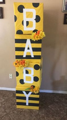 a yellow and black striped baby sign with flowers on the bottom that says, baby