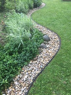 a garden with rocks and grass in the middle, along side a path that leads to a grassy area