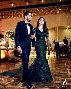 a man and woman dressed in formal wear walking down the dance floor at an event