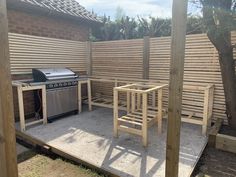 an outdoor kitchen with grill, table and chairs