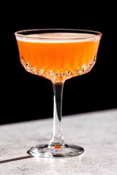 a glass filled with orange liquid on top of a table