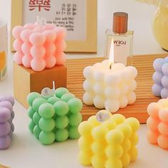 candles with different colors and shapes are on display in front of other small ones, including one candle