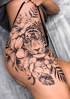 a woman's leg with a tiger and flowers tattoo on it