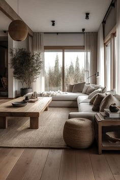 a living room filled with lots of furniture next to a wooden table and large windows