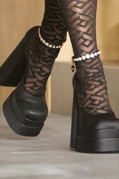 a woman wearing black high heeled shoes and patterned tights