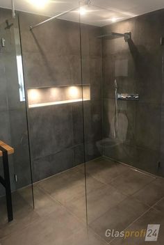 a bathroom with a walk in shower next to a wooden table and counter top sink