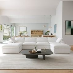 a living room filled with white furniture and lots of windows