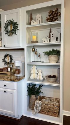 a kitchen with white cabinets and shelves filled with christmas decorations on top of it's counters