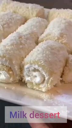 a white plate topped with three pieces of food covered in powdered sugar and icing