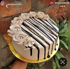 a cake decorated with white and black icing on top of a gold platter