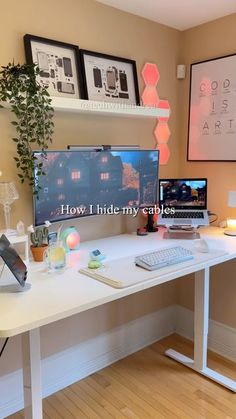 a computer desk with a laptop and monitor on it in front of two framed pictures