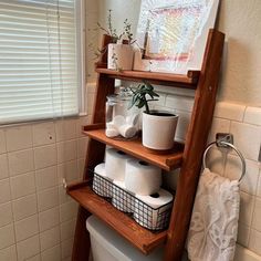 a bathroom with a ladder shelf over the toilet and various items on top of it