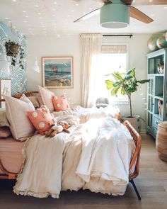 a bed with white sheets and pillows in a bedroom next to a bookcase filled with books