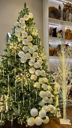 two christmas trees are decorated with white balls and lights in the store's holiday decorations