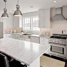 a large kitchen with white cabinets and marble counter tops, along with stainless steel appliances