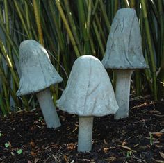 three stone mushrooms sitting on the ground in front of some bamboo trees and grass,