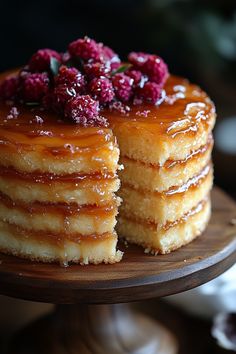 a stack of pancakes topped with raspberries on top of a wooden cake plate