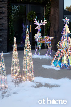 lighted christmas trees in front of a building with lights on them and an antelope