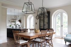 a dining room table surrounded by chairs and hanging lights