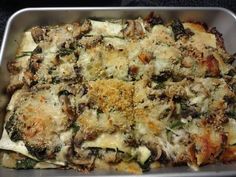 a casserole dish with mushrooms, spinach and cheese in a metal pan