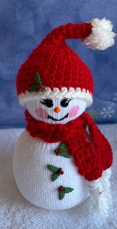 a knitted snowman with a red hat and scarf on it's head