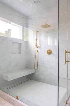 a walk in shower sitting next to a window with gold fixtures on the walls and floor