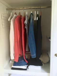 an open closet with clothes hanging on the rails