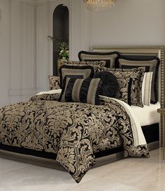 a bed with black and gold comforters in a room next to a chandelier