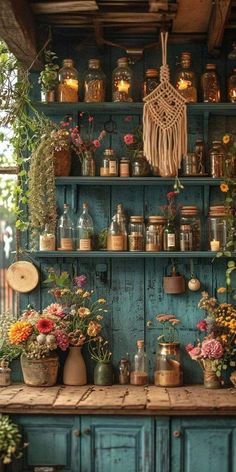 an old fashioned kitchen with lots of pots and pans on the shelves, flowers in vases