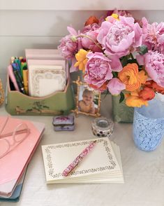 a vase filled with pink and yellow flowers sitting on top of a table next to other items