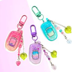 two cell phones with key chains attached to them on a white and pink background,