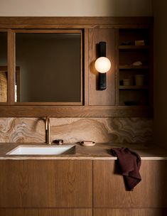 a bathroom with wooden cabinets and a white sink under a light on the wall above it