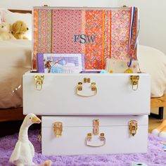 two white suitcases sitting on top of a purple rug in front of a bed