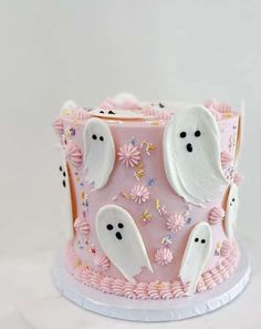 a pink cake with ghost decorations on it