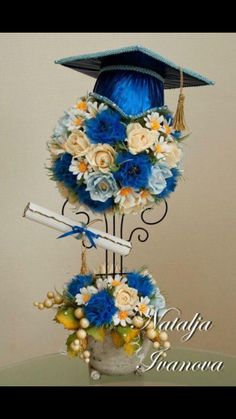 a blue graduation hat on top of a bouquet of flowers and other decorations in a vase