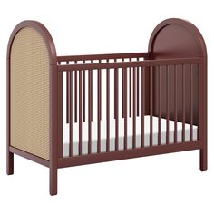 a wooden crib with a white sheet on the bottom and brown trim around it