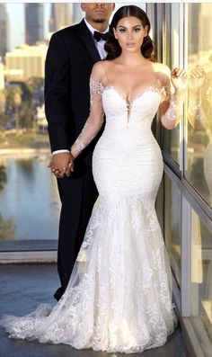 a man and woman standing next to each other in front of a glass wall holding hands