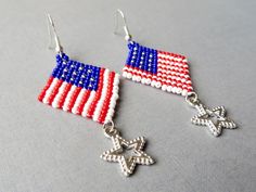 red, white and blue beaded earrings with stars on the bottom are hanging from silver hooks