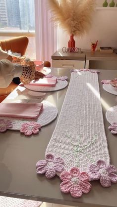 the table is set with pink crocheted placemats