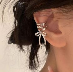 a close up of a person's ear wearing an ear cuff with two bows on it