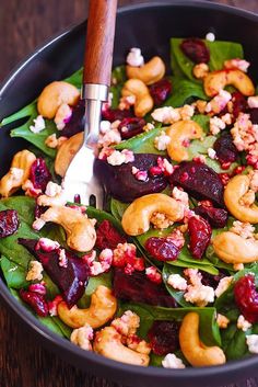 spinach salad with roasted beets, walnuts and cranberries in a black bowl