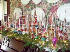 a table topped with lots of plates and christmas decorations next to a wall covered in flowers