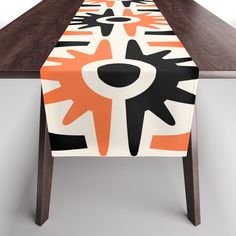 an orange and black table runner sitting on top of a wooden table